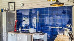 Una cocina con azulejos azules, un refrigerador de acero inoxidable, una estufa y un lavamanos.