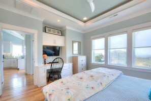 Une chambre à coucher avec un lit, un bureau, une chaise et un téléviseur. Il y a une fenêtre donnant sur l’extérieur.