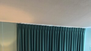 Un soggiorno con una tenda verde acqua, un divano, una lampada e un tavolo da pranzo.