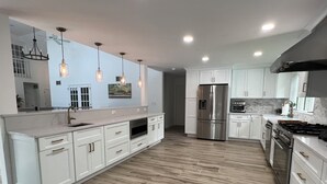 Una cucina moderna con mobili bianchi, un frigorifero in acciaio inossidabile, forno integrato e piano cottura a gas.