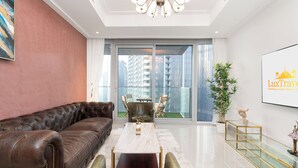A modern living room with a leather sofa, a glass-top coffee table, and a view of high-rise buildings through large windows. - Lux BnB Opera Grand Burj Khalifa & Fountain View (Dubai)