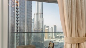 A room with a view of a cityscape, including tall buildings and a bridge. There is a wooden chair and a small table with a cushion. - Lux BnB Opera Grand Burj Khalifa & Fountain View (Dubai)