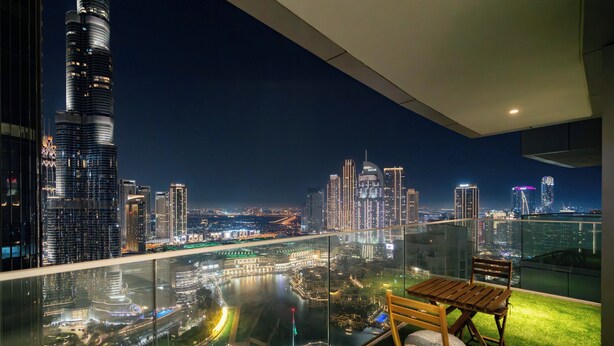 A balcony with a glass railing overlooking a cityscape at night, featuring a view of a tall skyscraper and other buildings. - Lux BnB Opera Grand Burj Khalifa & Fountain View (Dubai)