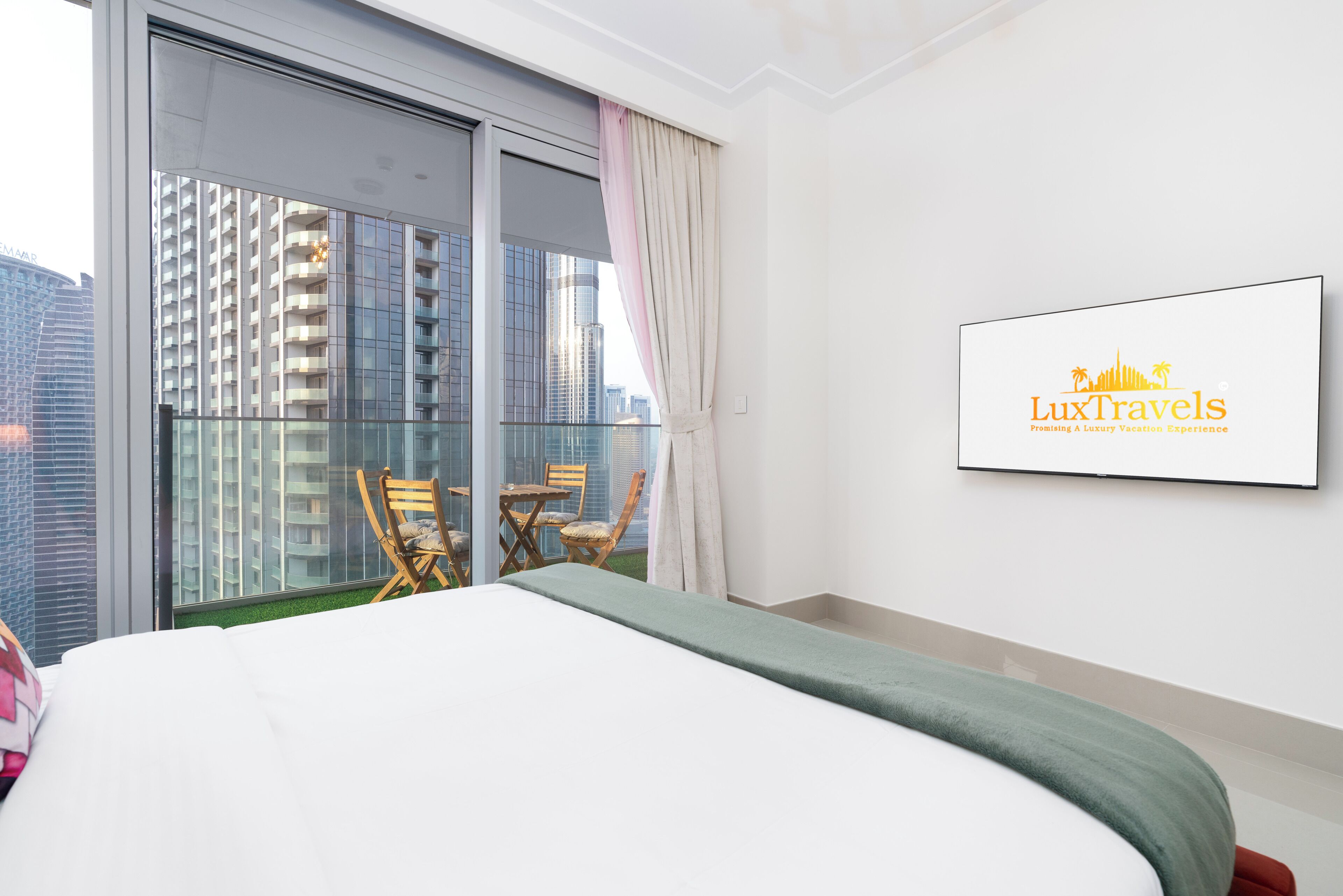 Een hotelkamer met een bed, een balkon met stoelen en uitzicht op de stad.