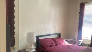 Une chambre à coucher comprenant un lit, un bureau, une chaise, une lampe et un téléviseur.