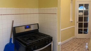 Une cuisine équipée d’une cuisinière à gaz, d’un balai et d’un pare-feu en carreaux.