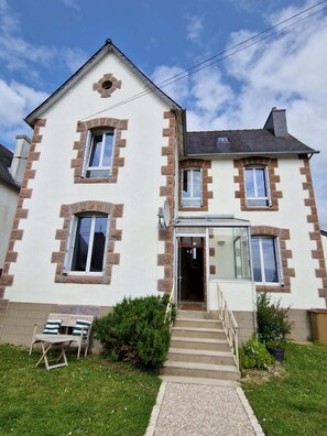 Une maison à deux étages avec une entrée à l’avant, un petit porche et un escalier menant à la porte.