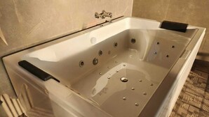 A modern, rectangular bathtub with a clear interior, multiple jets, and a control panel. - Adrista Divine Cottages (Arambol)