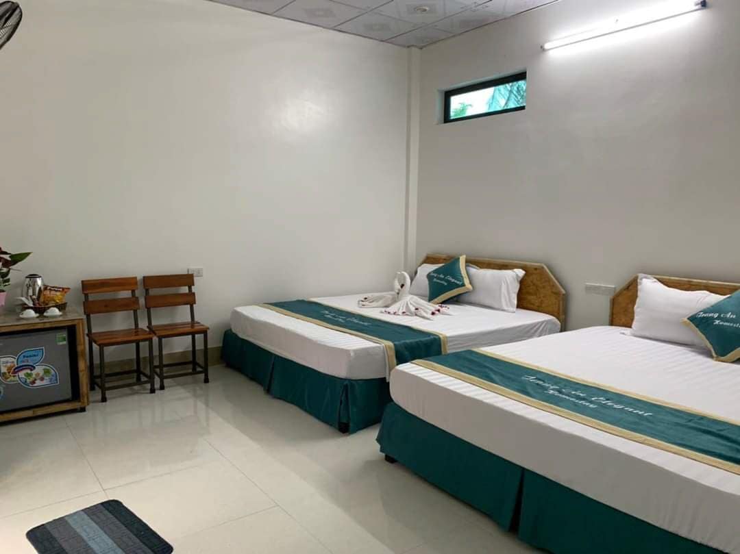 Une chambre d’hôtel avec deux lits, un bureau, des chaises et une petite fenêtre.