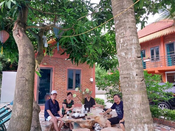 A group of people sitting at a table outdoors with a brick building in the background.