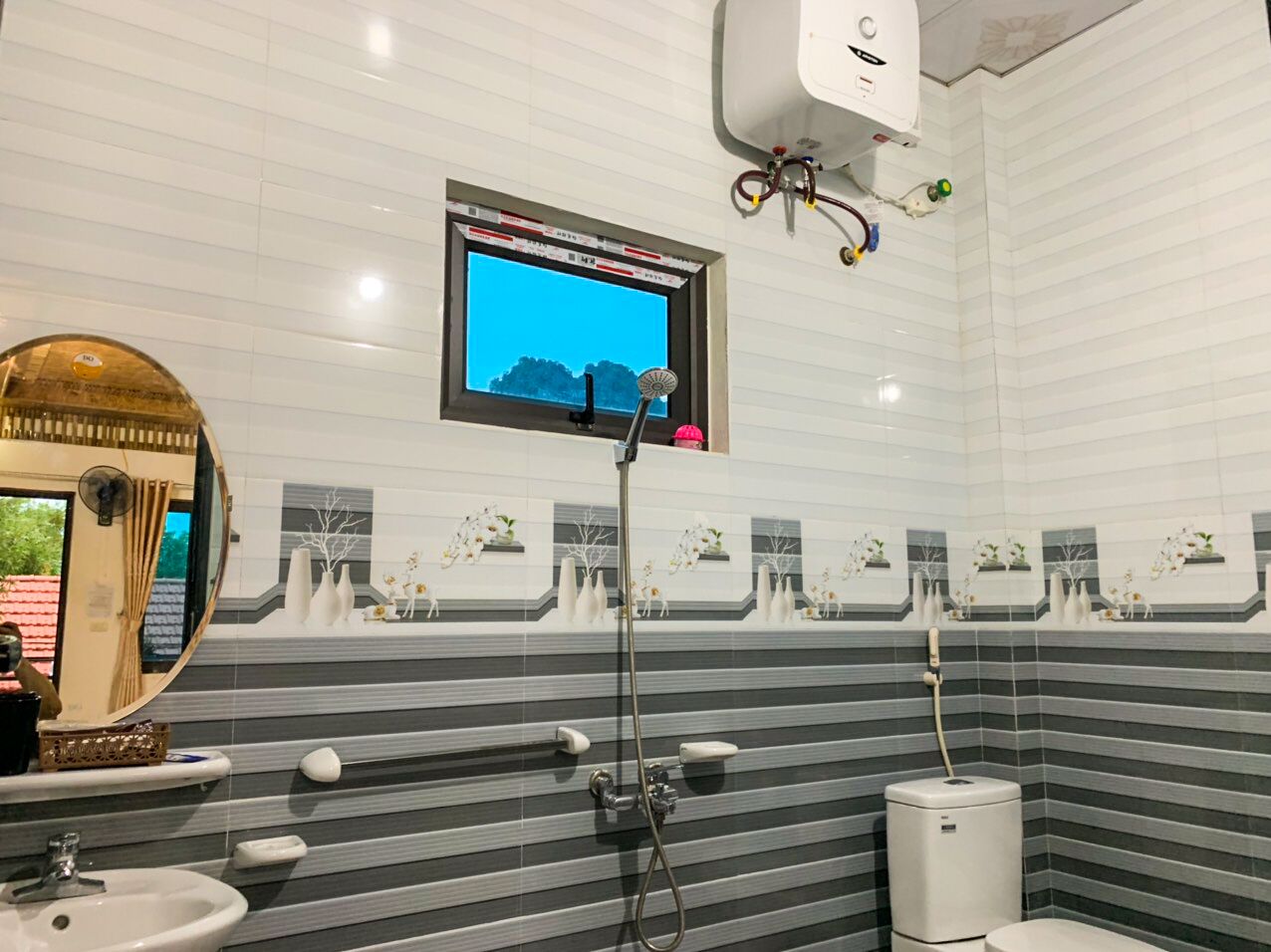 A modern bathroom with a large mirror, a shower, and a toilet.