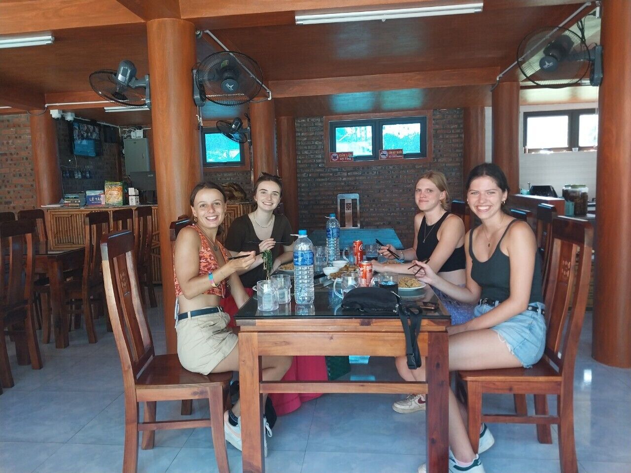A group of people seated around a wooden table in a restaurant with brick walls and wooden furniture.