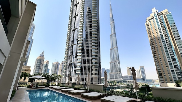 A rooftop pool area with lounge seating and a view of the Burj Khalifa and surrounding high-rise buildings. - LuxBnB Dubai Opera Act-1 Boulevard Views (Dubai)