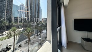 A modern hotel room with a large window offering a view of tall buildings and palm trees. - LuxBnB Dubai Opera Act-1 Boulevard Views (Dubai)