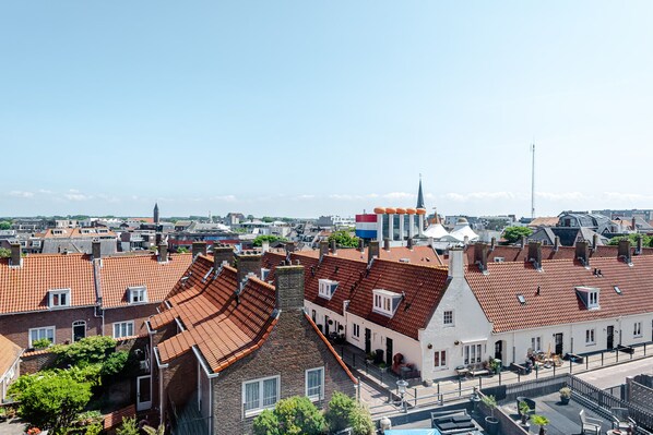 A residential area with red-tiled roofs, white buildings, and a church steeple. - Albatros aan Zee - Studio (Zandvoort)