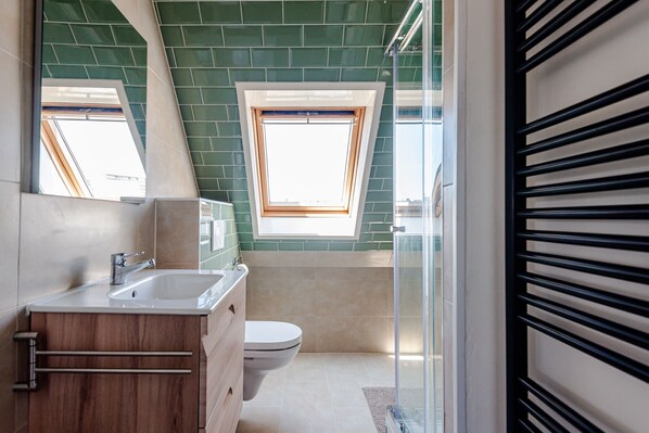A modern bathroom with a skylight, a shower, and a toilet. - Albatros aan Zee - Studio (Zandvoort)