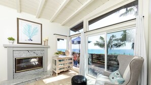 A living room with a fireplace, a sofa, and a view of the ocean. - Historic Olde Del Mar Hacienda | Panoramic Ocean Views (Del Mar)