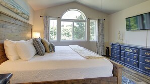 Ein Schlafzimmer mit einem großen Bett, einem hölzernen Kopfteil, einem Deckenventilator, einem Fernseher und einer Kommode mit Schubladen.