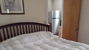 Una cama con cabecera de madera en una habitación con una puerta y un cuadro en la pared.