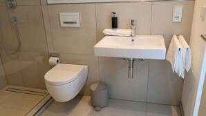 A modern bathroom with a toilet, sink, and shower.