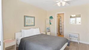 A bedroom with a bed, a ceiling fan, a nightstand, a dresser, a framed picture, and a window. - Ocean & Bay Views, Steps to Beach (Ocean City)