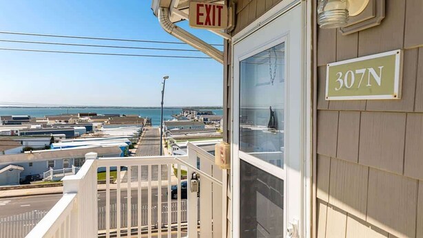 A building with an 'EXIT' sign, a '307N' address sign, and a view of a coastal area with buildings and a body of water. - Ocean & Bay Views, Steps to Beach (Ocean City)