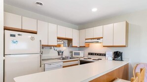 A modern kitchen with white cabinets, a built-in microwave, a stove, and a dishwasher. - Ocean & Bay Views, Steps to Beach (Ocean City)