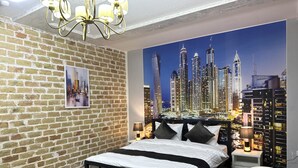 A bedroom with a brick wall, a cityscape mural, a bed, a chair, and a chandelier. - Ayva Hotel (Tashkent)