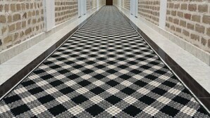 A long hallway with brick walls, white doors, and a black and white checkered carpet. - Ayva Hotel (Tashkent)