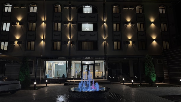 A hotel facade with multiple windows, a central entrance, and a fountain in the courtyard. - Ayva Hotel (Tashkent)