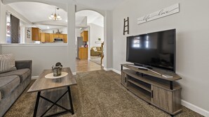 A living room with a TV, a sofa, a coffee table, and a kitchen in the background. - Large Yard~Great Location~Pet Friendly~Fast Wifi (Boise)