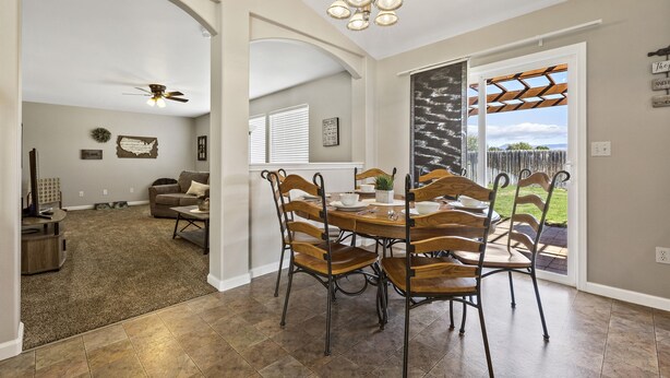 A dining area with a round table and chairs, a ceiling fan, and a view of the outdoors. - Large Yard~Great Location~Pet Friendly~Fast Wifi (Boise)