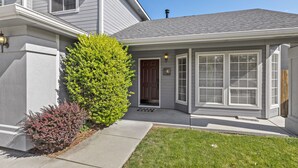 A residential house with a grey exterior, a front porch, a green tree, and a well-maintained lawn. - Large Yard~Great Location~Pet Friendly~Fast Wifi (Boise)