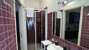 A bathroom with a walk-in shower, a white sink, and a large mirror.