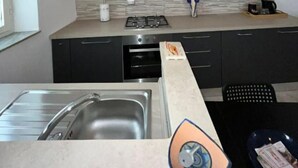 A modern kitchen with dark cabinets, a stainless steel sink, and a tiled backsplash.