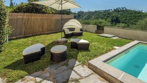 Patio con piscina, mobiliario exterior y cerca de bambú.