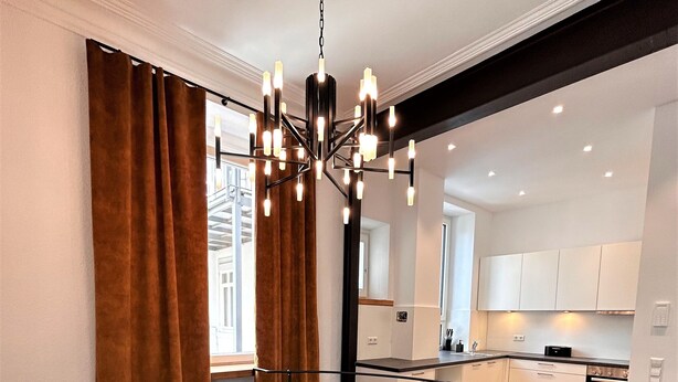 Een modern interieur met een trap, een kroonluchter en een keukenhoek.