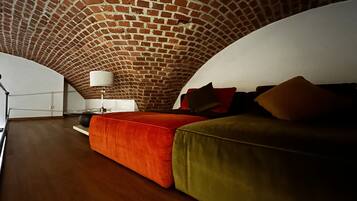 Una camera da letto mansardata accogliente, con soffitto in mattoni, pavimento in legno e letto con biancheria rossa e verde.