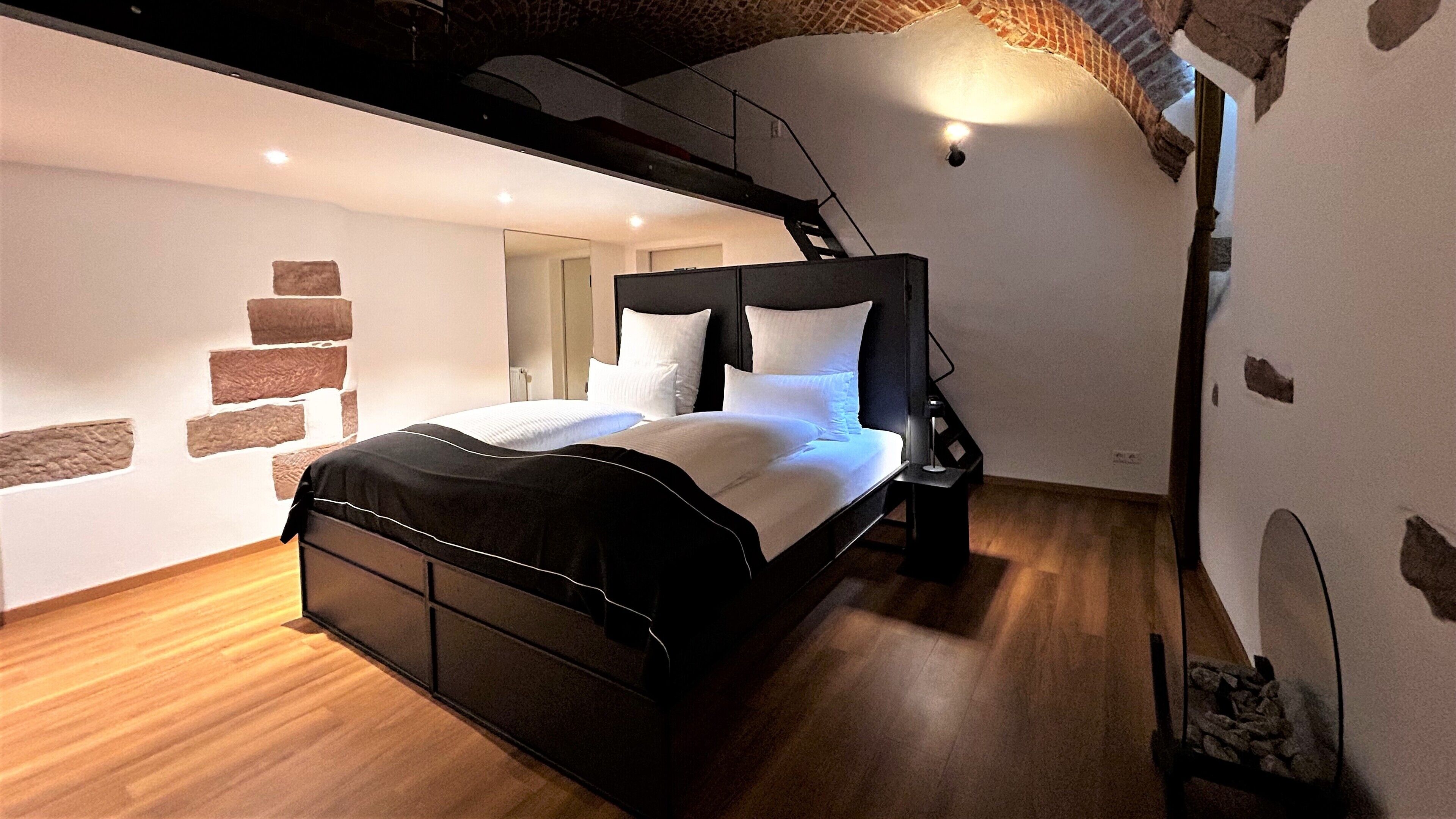 Een moderne slaapkamer met een bed, houten vloeren en een wand met een bakstenen ontwerp.