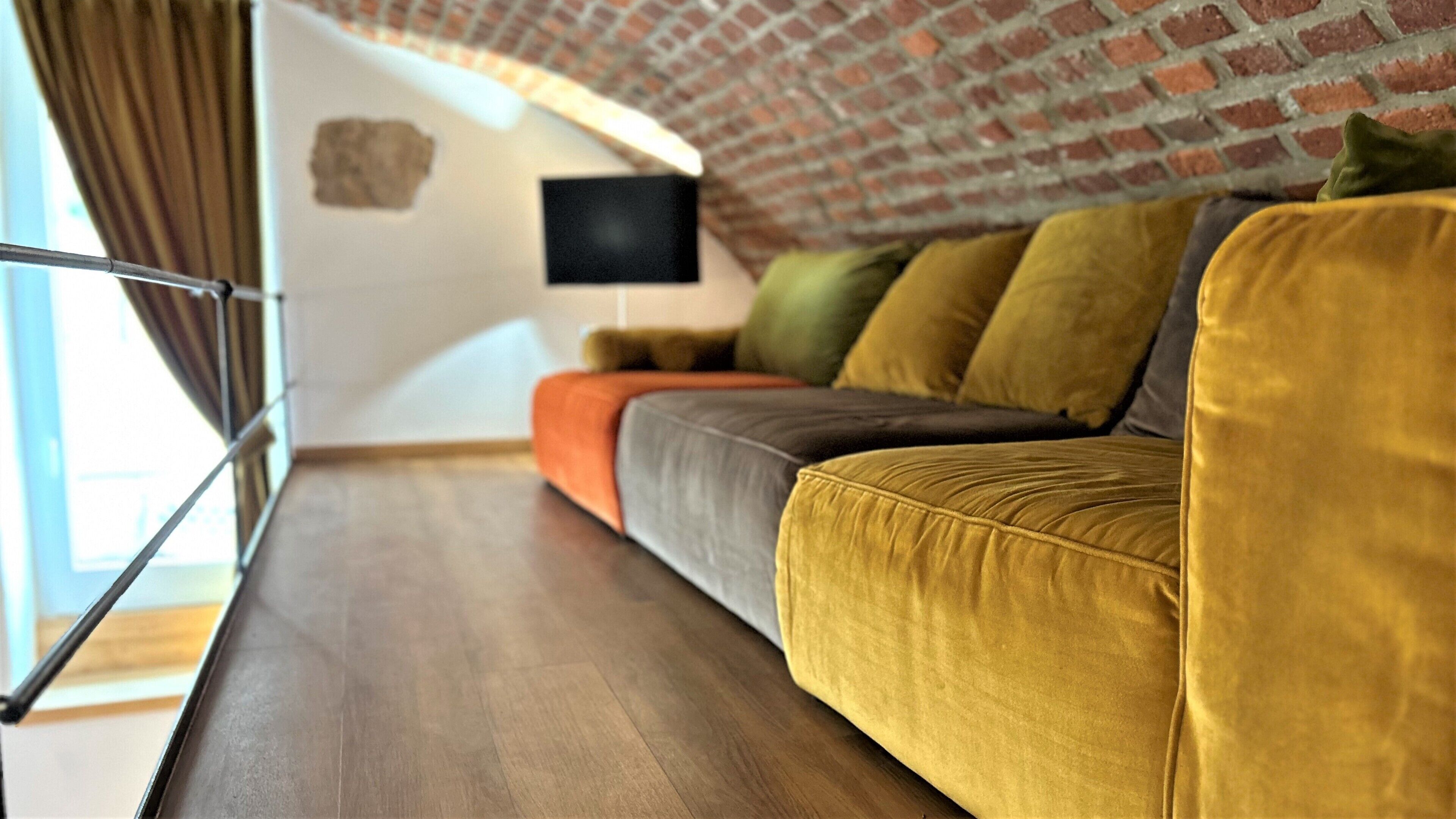 Uma sala de estar moderna com um sofá, almofadas e uma televisão de tela plana.