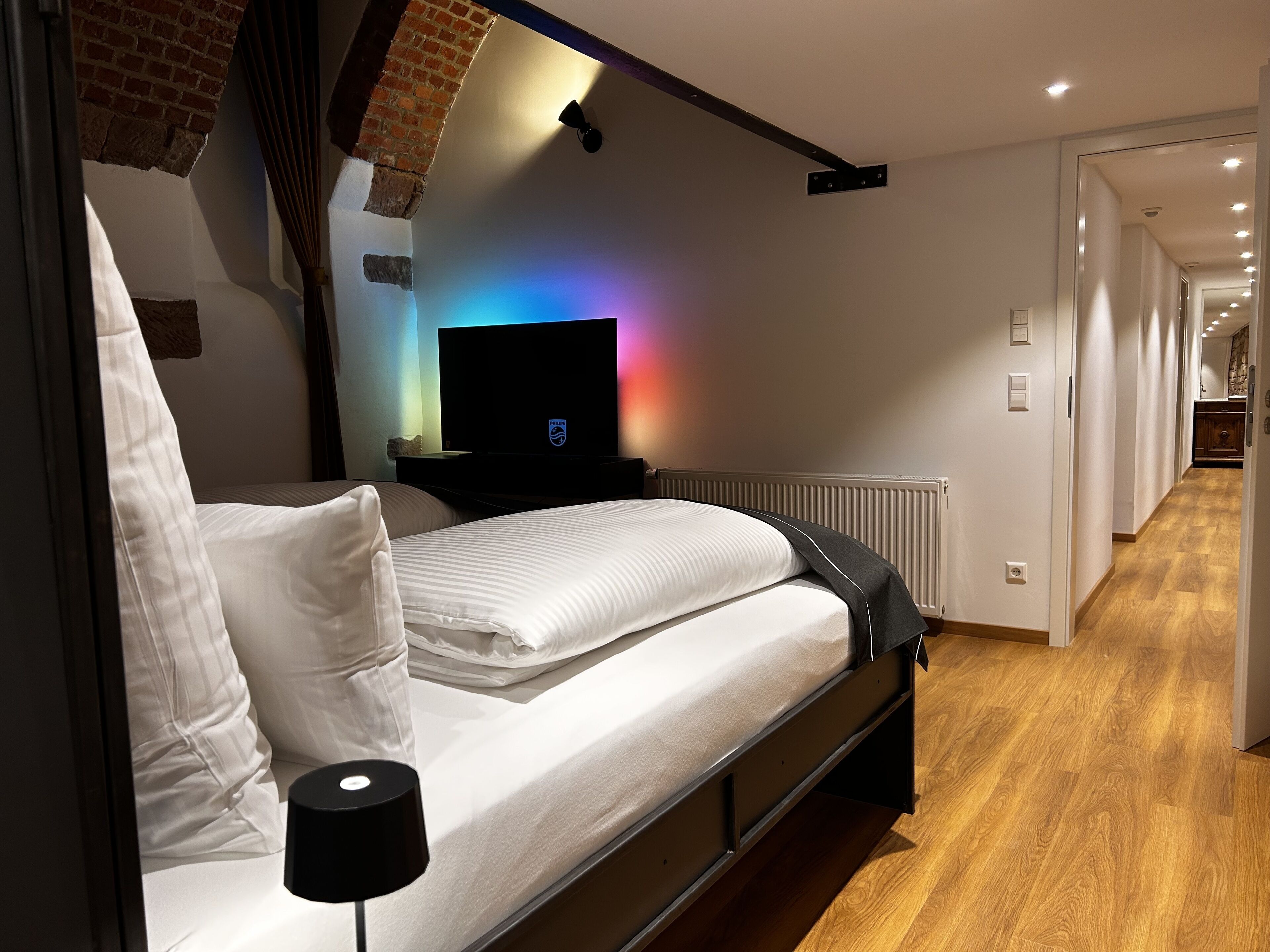 Une chambre à coucher moderne avec un lit, un téléviseur et une lampe.