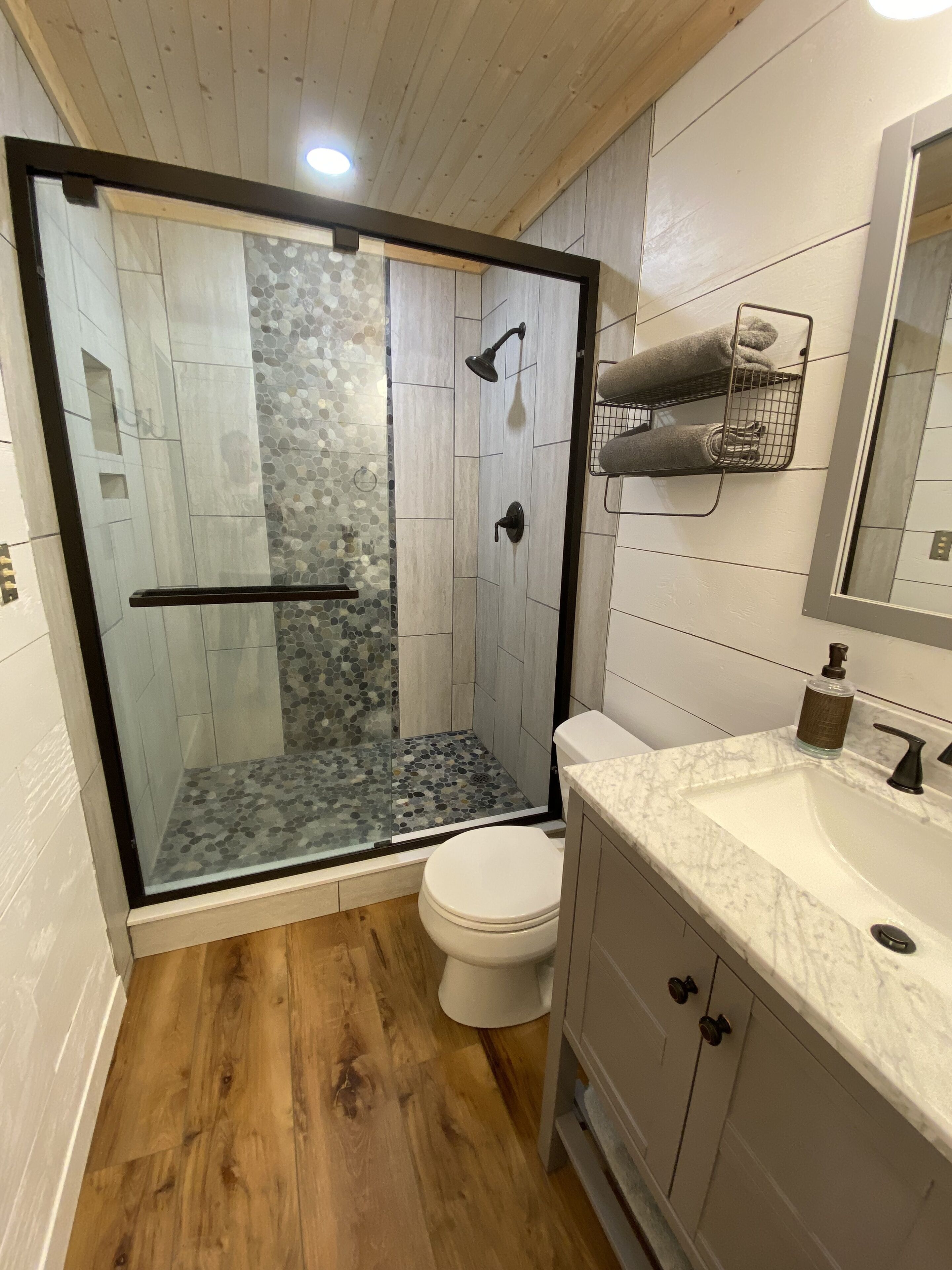A modern bathroom with a glass-enclosed shower, a white toilet, and a marble sink.