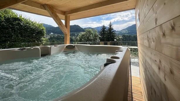 A hot tub with a wooden ceiling and a view of mountains.