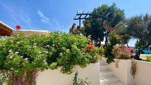 A white building with a staircase, a pergola with flowers, and a clear blue sky. - Aura Bozcaada (Bozcaada)