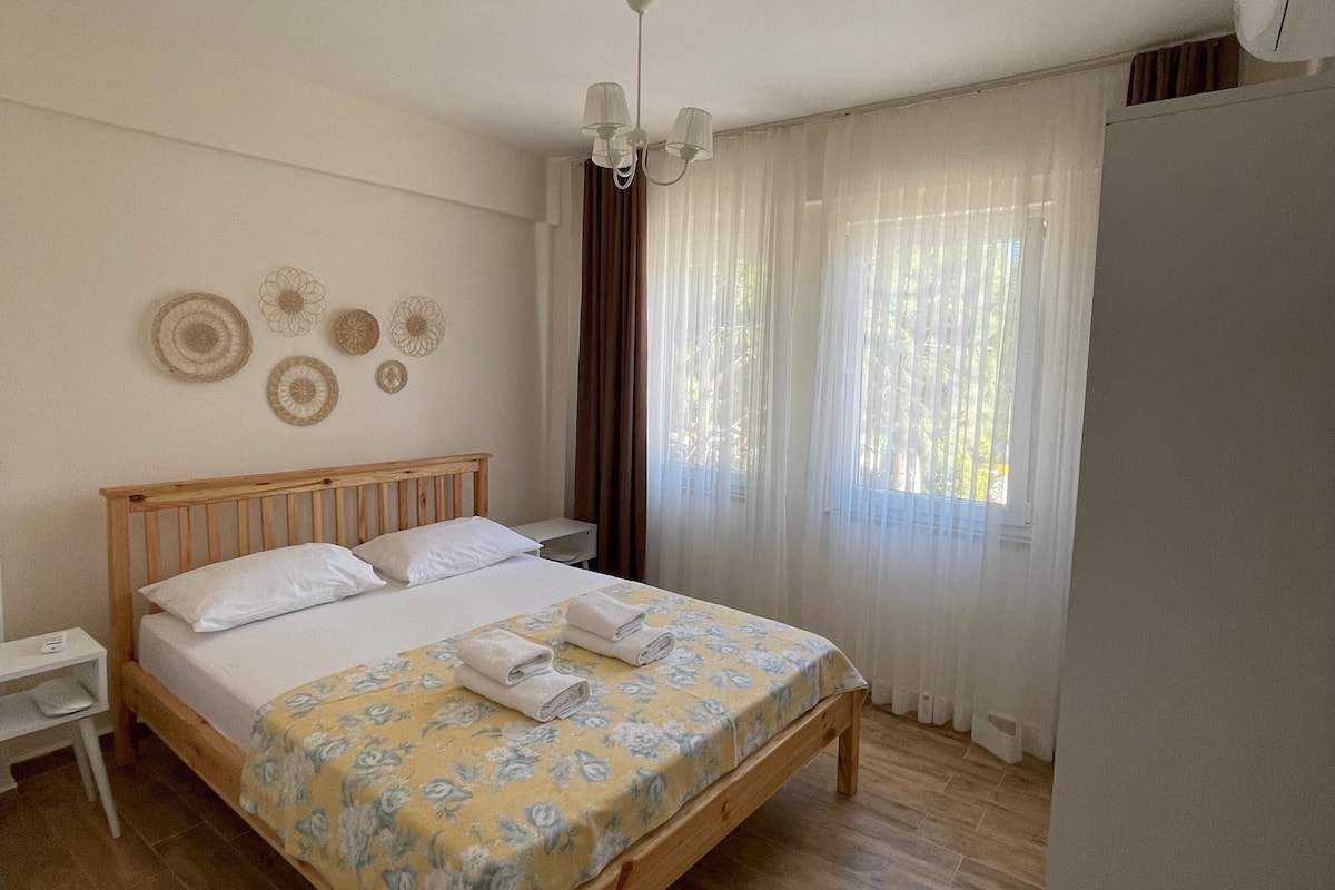 Una cama bien hecha con una colcha estampada con flores, un cabecero de madera y una mesita de noche con una lámpara.