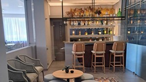A modern bar area with a bar counter, stools, and a variety of bottles and glasses. - Villa Rey Hotel & Spa (Vila de Rei)