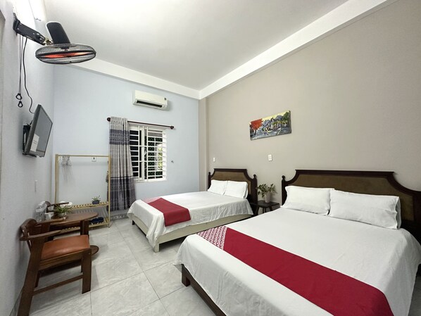 A hotel room with two beds, a desk, a chair, a TV, an air conditioner, a window with curtains, and a painting on the wall. - OYO 1187 Suoi Da Motel (Da Nang)