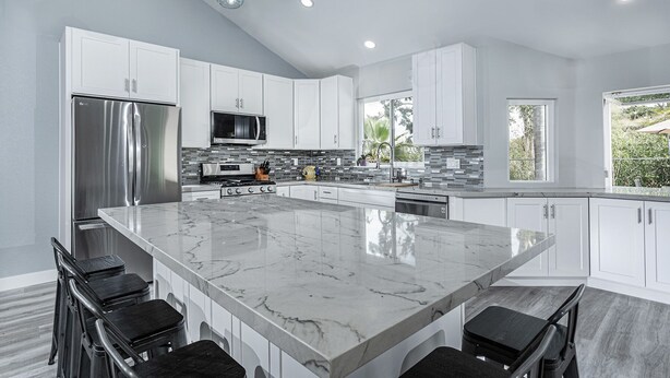 A modern kitchen with a large marble island, stainless steel appliances, and white cabinetry. - ~OPEN 9/14-17! Beachy Lagoon Getaway! Pool & Spa, Pets OK, Remodeled!~ (Carlsbad)