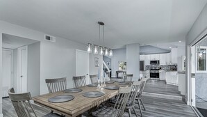 A modern kitchen with stainless steel appliances, a wooden dining table with chairs, and a view to the outside. - ~OPEN 9/14-17! Beachy Lagoon Getaway! Pool & Spa, Pets OK, Remodeled!~ (Carlsbad)