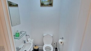 A small, compact bathroom with a toilet, sink, and mirror. - NightRest Homes 6 Bedroom Short & Long Term Smart Tv in each Room, Free Parking  (Oxley Park)